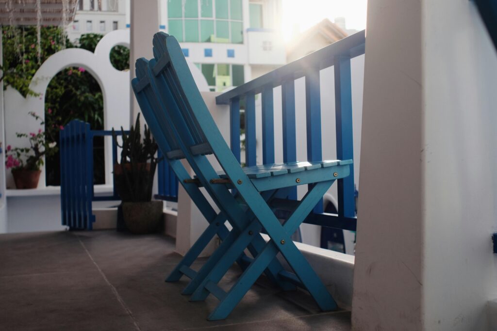 Stylish blue wooden chairs on a bright porch, perfect for relaxation and sunny ambiance.